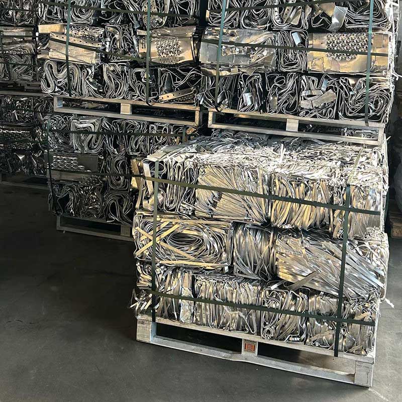 Gestapelte, gepresste Aluminiumbleche und -profile auf Paletten in einer Lagerhalle, bereit für Recycling und Weiterverarbeitung.