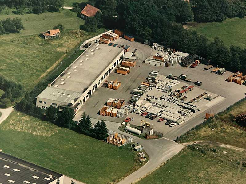 Historische Luftaufnahme des Aluminium Krüger Betriebsgeländes mit Lagerflächen, Containern und Fahrzeugen in ländlicher Umgebung