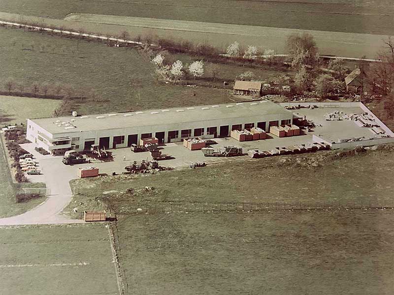 Historische Luftaufnahme des Aluminium Krüger Betriebsgeländes in ländlicher Umgebung mit Containern und Fahrzeugen auf dem Hof