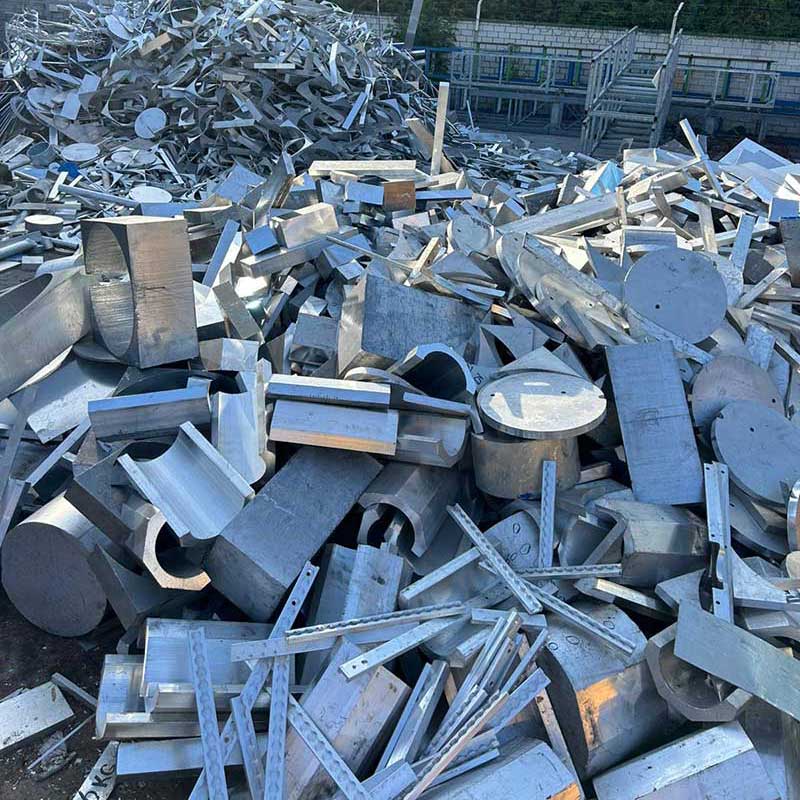 Gestapelte Aluminiumstücke und Metallabschnitte verschiedener Formen auf dem Betriebsgelände.