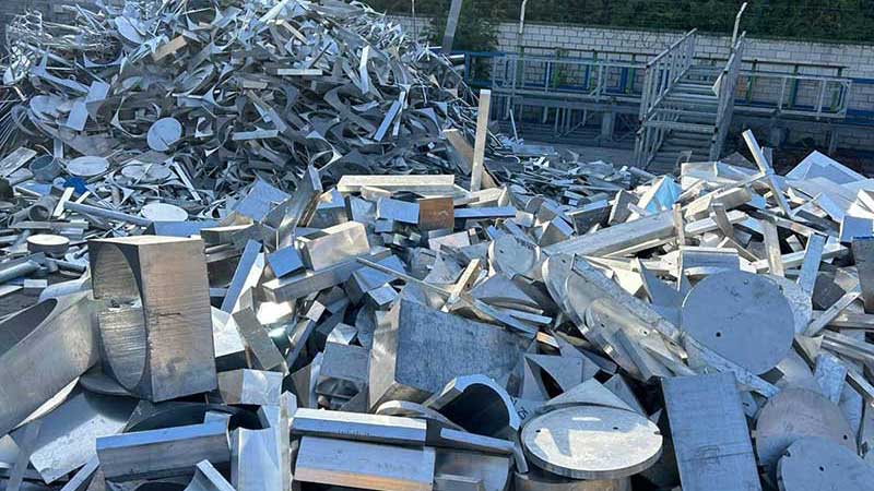 Gestapelte Aluminiumstücke und Metallabschnitte verschiedener Formen auf dem Betriebsgelände.
