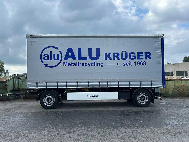 Anhänger mit Plane und großem Aluminium Krüger Logo auf dem Firmengelände, Aufschrift "Metallrecycling seit 1968"