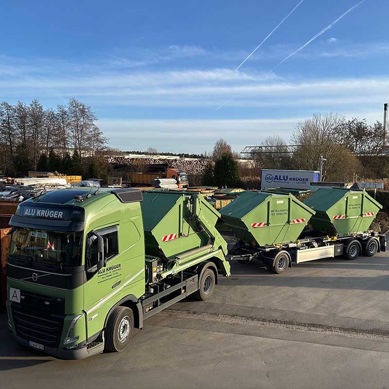 Gr&uuml;ner Lkw mit Abrollcontainern steht auf dem Betriebsgel&auml;nde